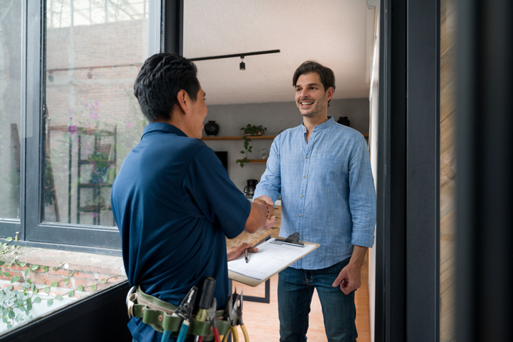 Homeowner and plumber for sewer line maintenance shaking hands at the door